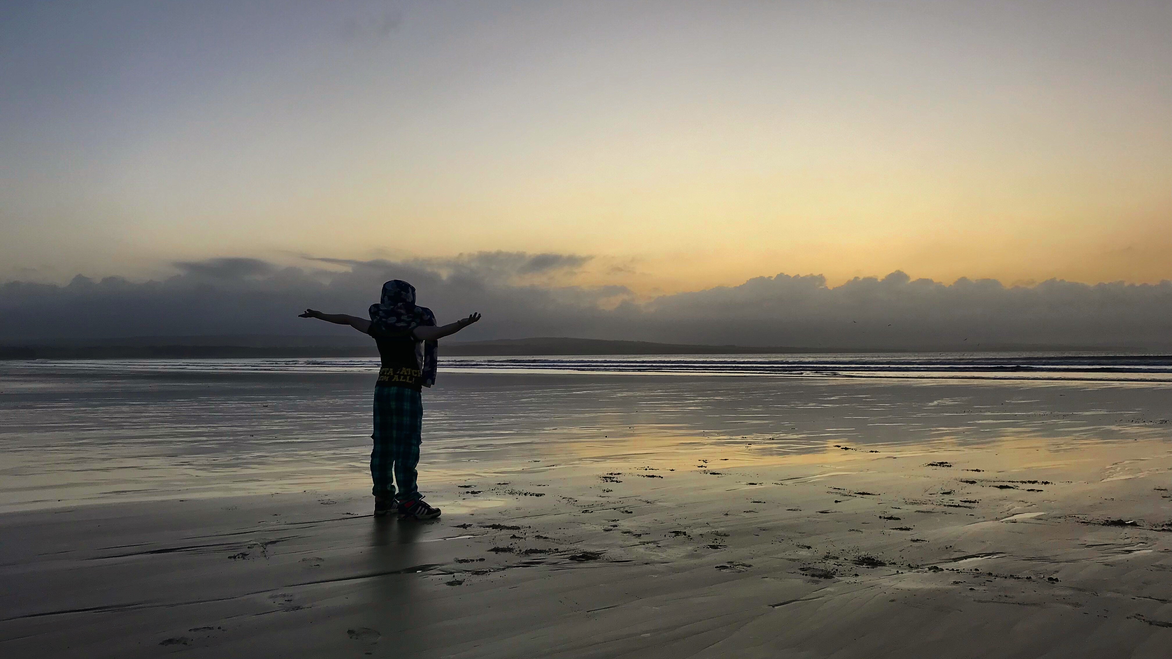 Boy on beach in sunset scene