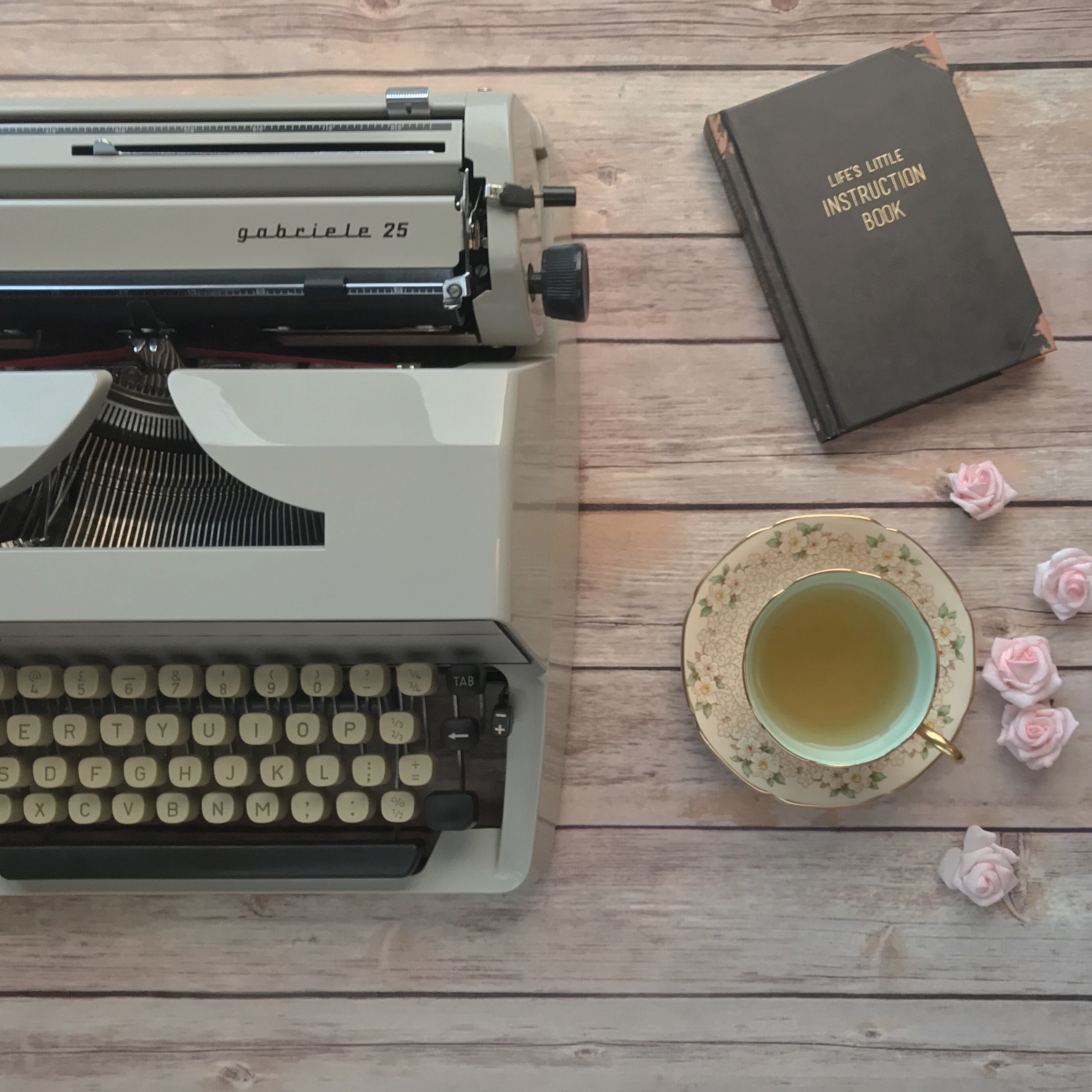 Tyepwriter, cup of tea and 'Life's Little Instruction Book' on table
