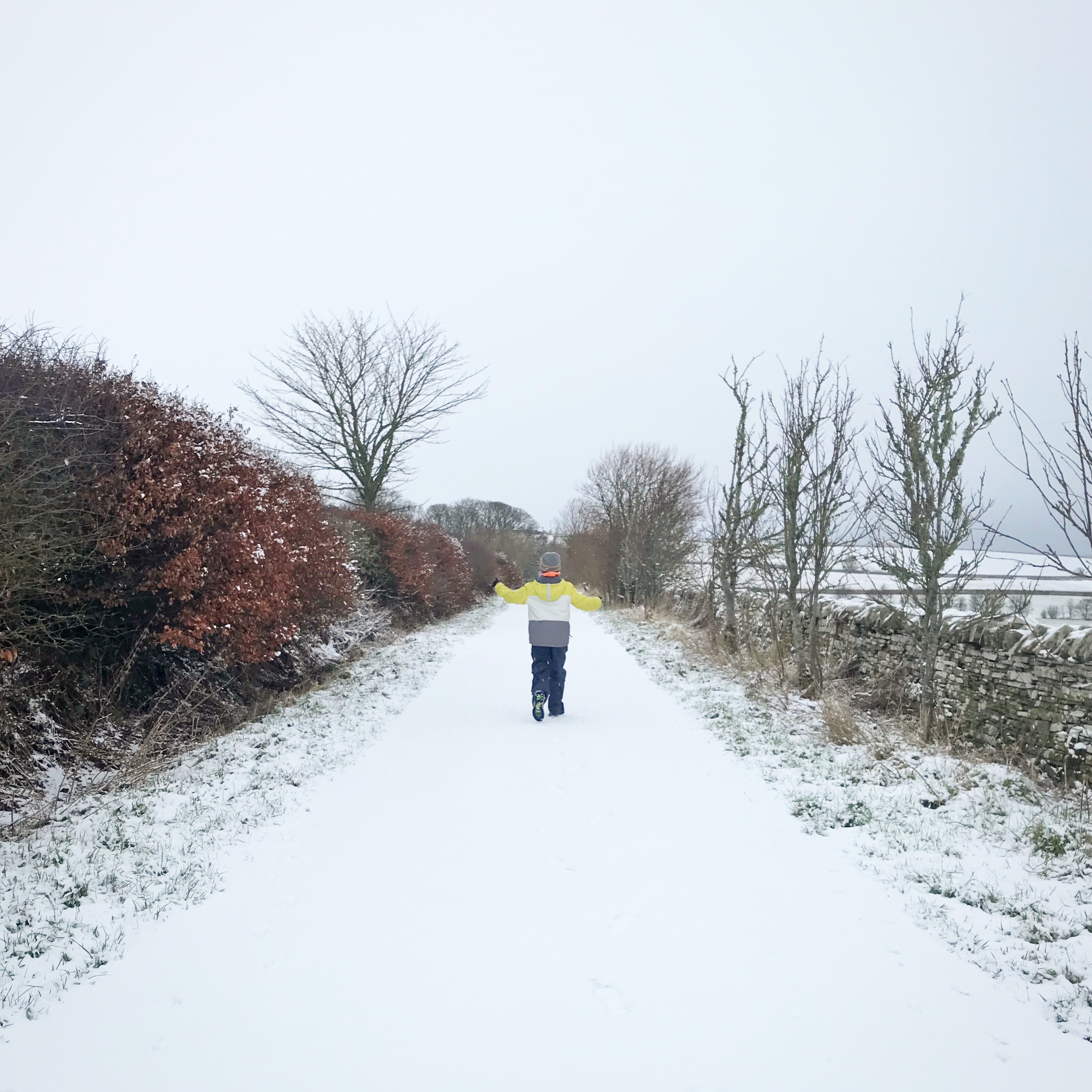 Photo of boy walking down snowy country lane