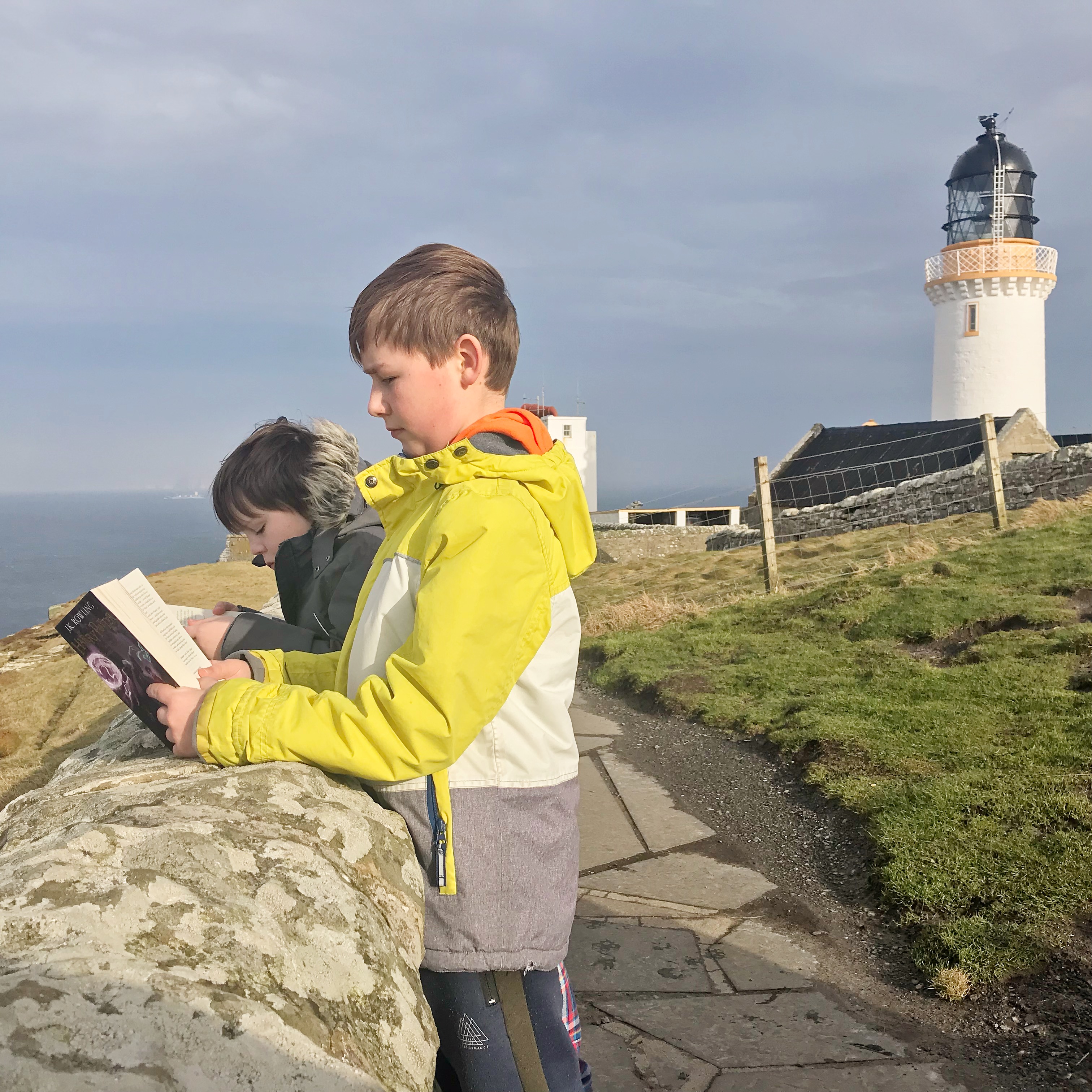 Boys reading next to lighthouse at Dunnet Head, Caithness