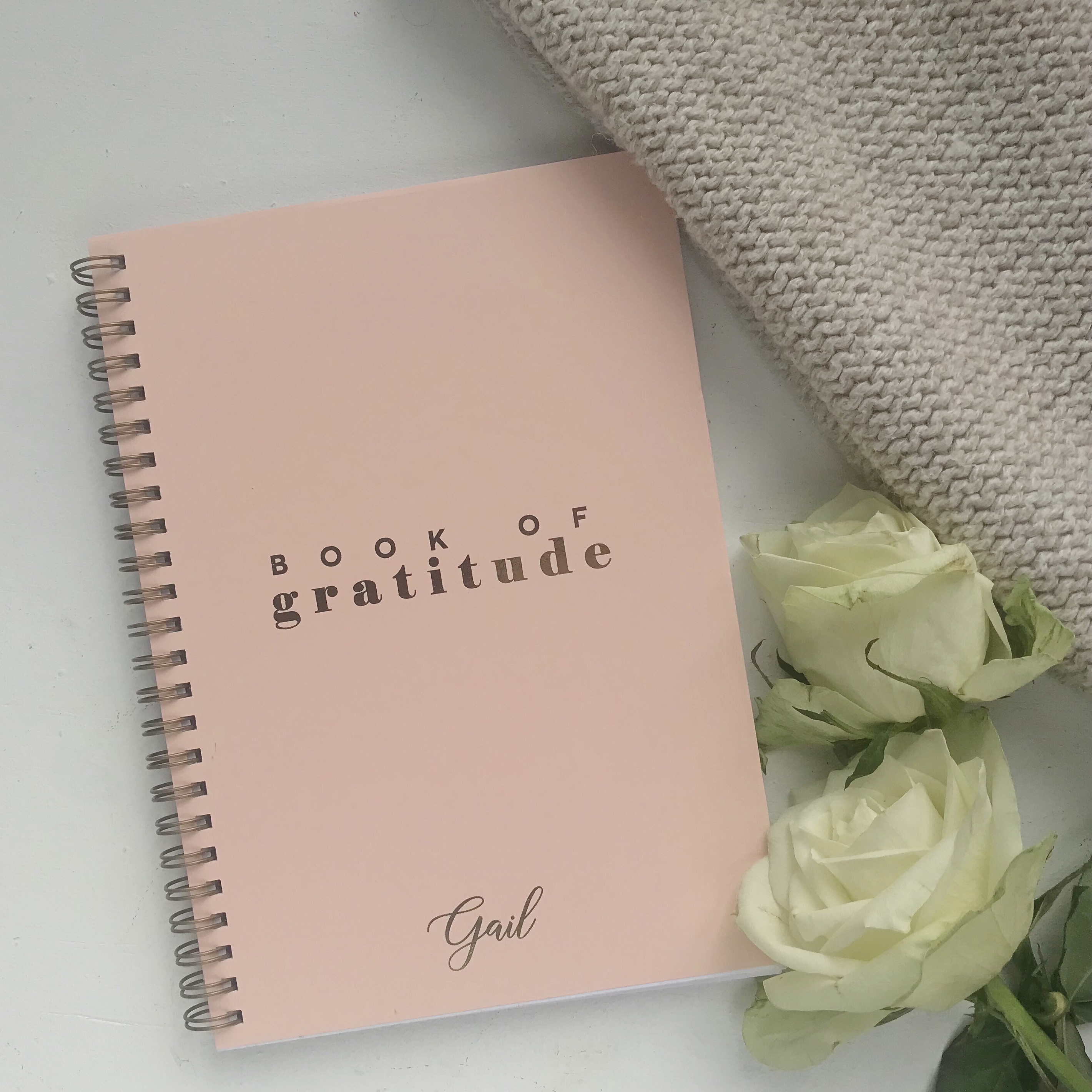Flatlay picture of personalised gratitude journal with flowers and blanket