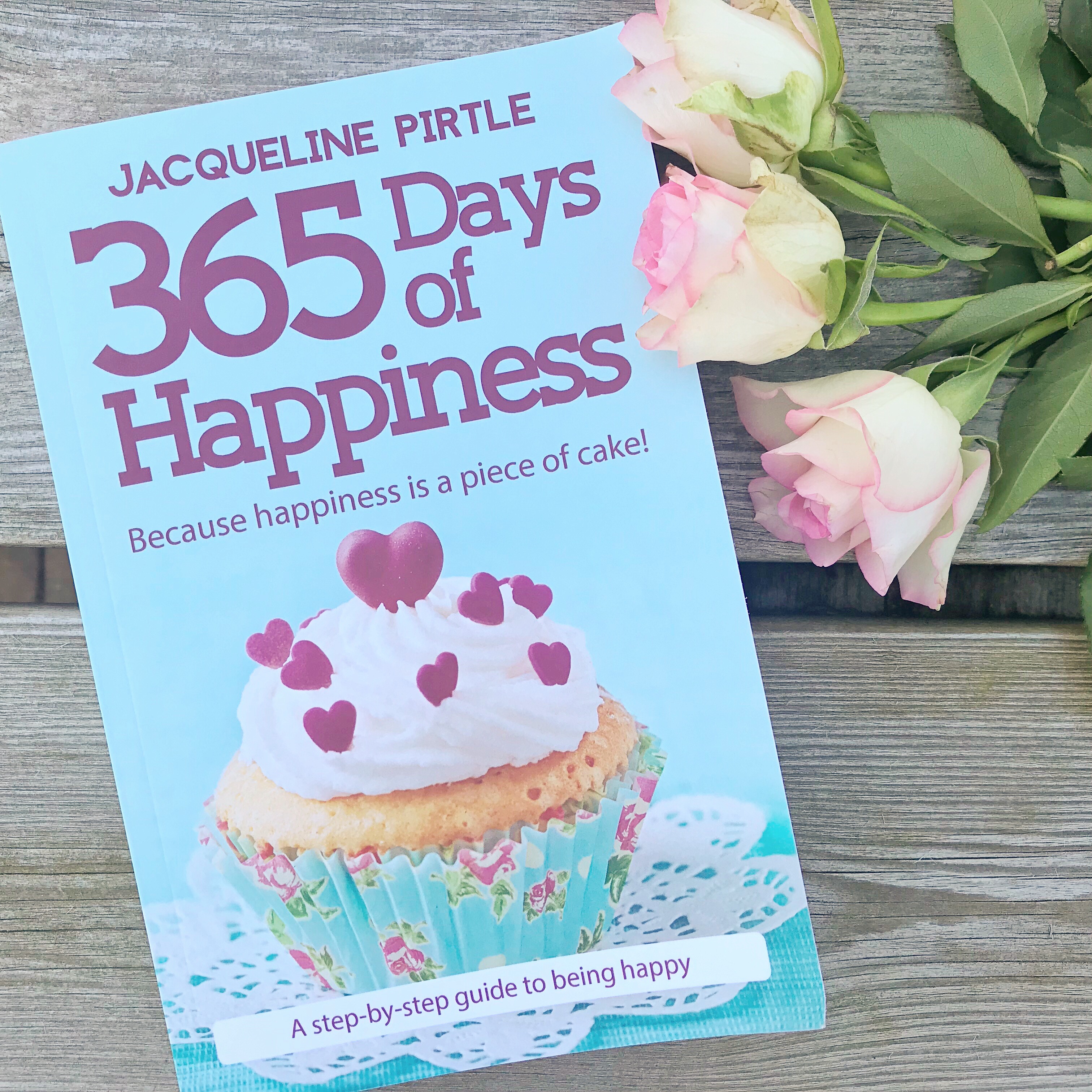 Photo of '365 Days of Happiness' book on table with flowers