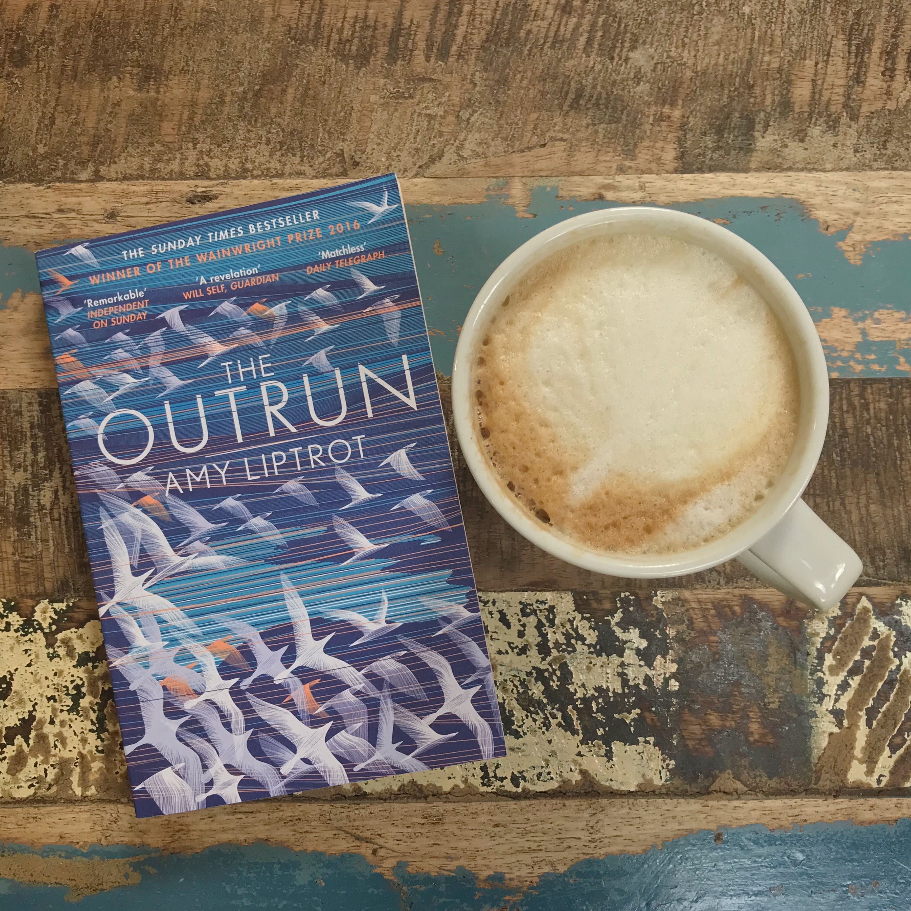Picture of The Outrun by Amy Liptrot on table with coffee