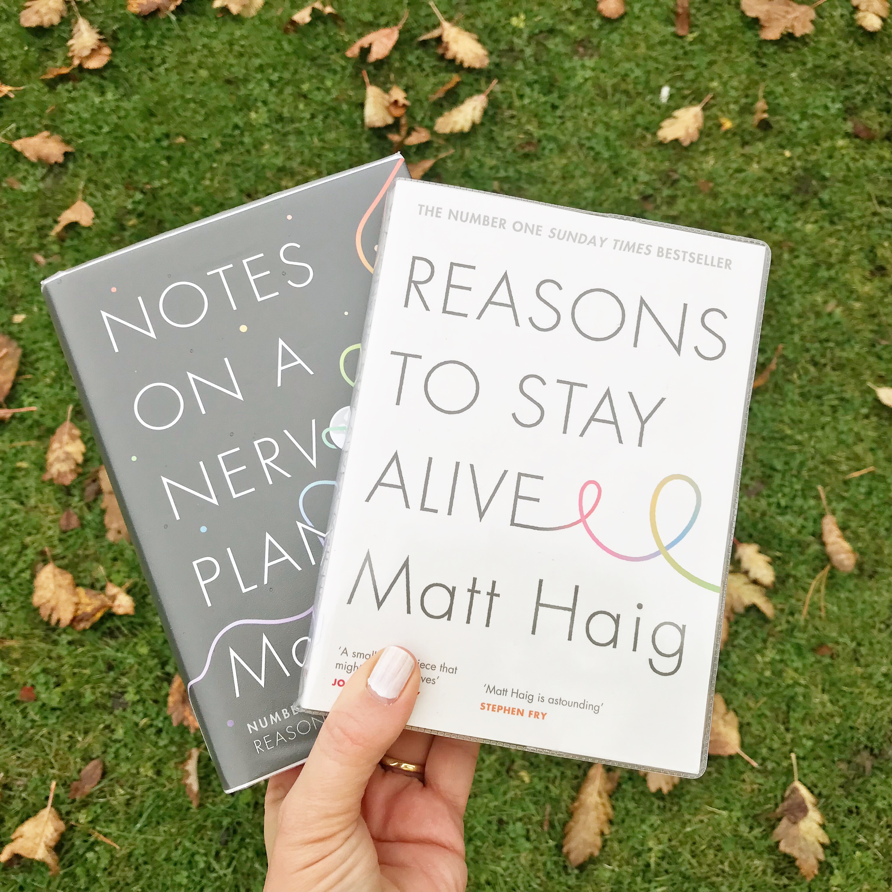 Photo of 'Reasons to Stay Alive' and 'Notes on a Nervous Planet' books against fallen leaves.